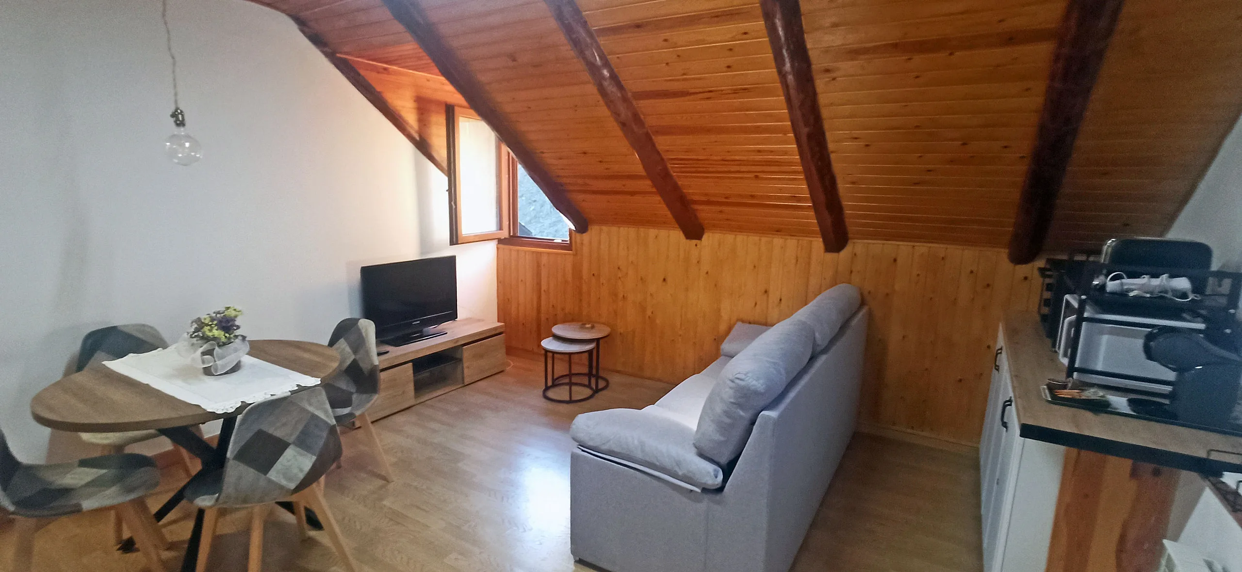 Sofá y mesa del salón, con la televisión y las vigas de madera